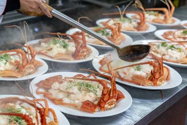 The chef's hand is operating the cooked lobster on the plate