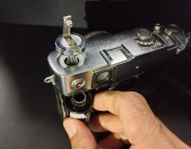 Man hand loading 35mm film on a vintage camera in a darkroom