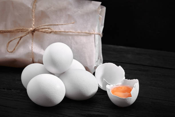 fresh chicken white eggs with hay on sack and rustic wood, organic farming on black background. healthy natural food - agriculture brown burlap cholesterol foto e immagini stock