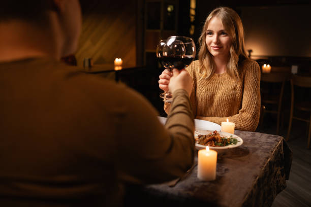 istock Young passionate couple having a romantic candlelight dinner at home, clinking wineglasses and drinking wine celebrating Valentines Day 1926891198