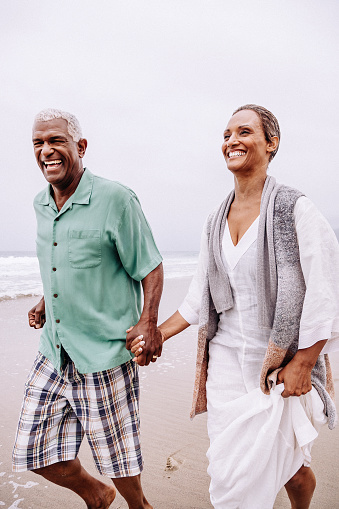 Senior African American couple walking with at sandy beach.