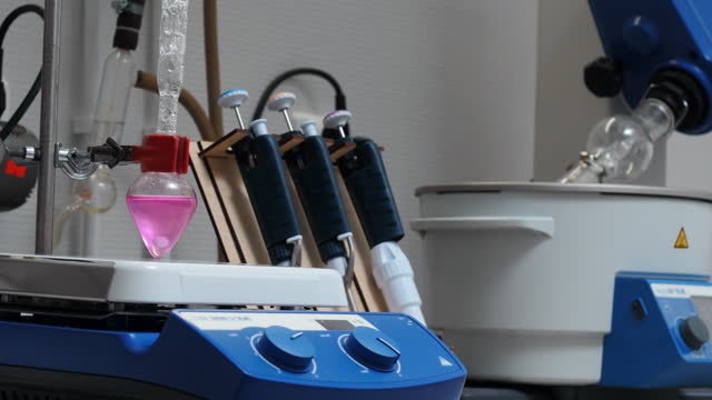 Equipment in chemical laboratory with rotating flasks. Stock footage. Rotating equipment and colored liquid in flask in laboratory. Chemical laboratory analyses with equipment.