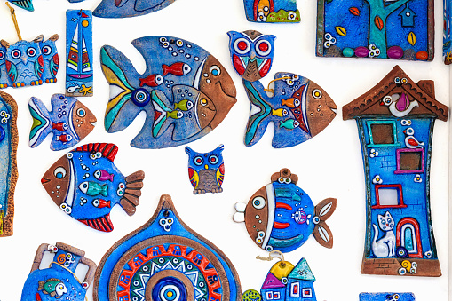 Handmade creative magnets: evil eye, fish, cats, owls, houses. Ceramic, blue, vibrant colors. Various colorful fridge magnets to remind travel. October 14, 2023. Bodrum, Turkey (Turkiye)