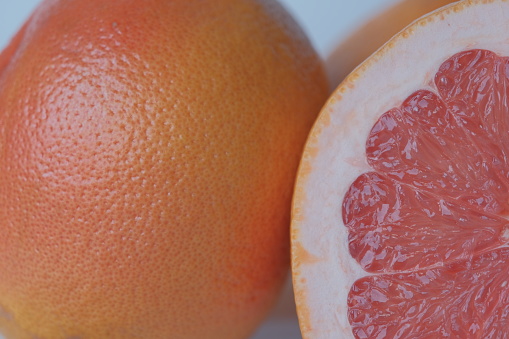 This is a close up photo of pink grapefruit sliced in half that is isolated on a white background with a drop shadow. High angle view, studio shot.