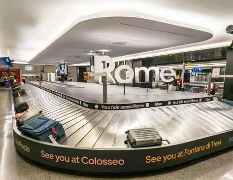 Rome, Italy - Luggage on a carousel in a baggage reclaim hall at Rome Fiumicino airport.