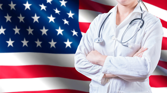 Female doctor with stethoscope on American flag. Unrecognizable female doctor with arms crossed on American flag, Health and care with the flag of United State