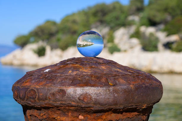 Glass ball lying on a rusty bollard, sunny day in autumn in Cres (Croatia)