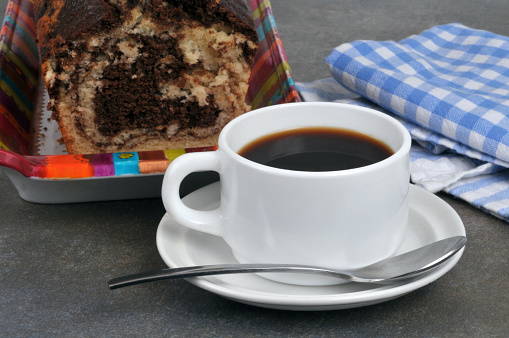 Cup of coffee with a spoon and a marble cake