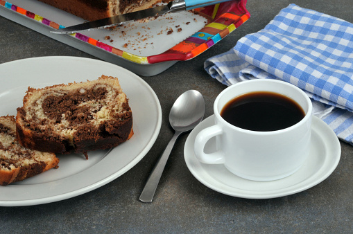 Cup of coffee with a spoon and slices of marble cake on a plate