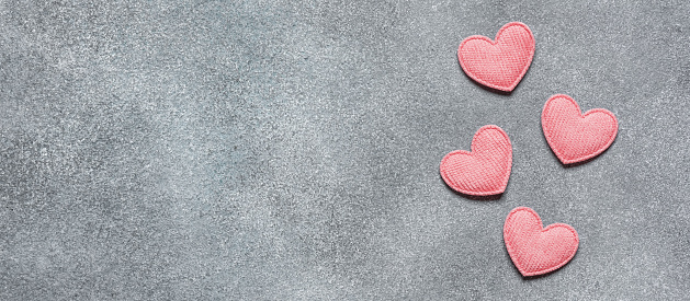 Pink hearts on a gray concrete background flat lay. Top view, copy space. Valentine's Day. Banner