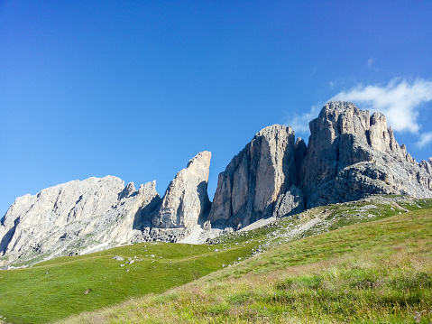 Clear summer sky over the Dolomites surrounded by green meadows
