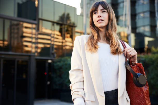istock Post-Work Stride: Young Professional in Suit Leaves Office, Purse in Hand 1927073052