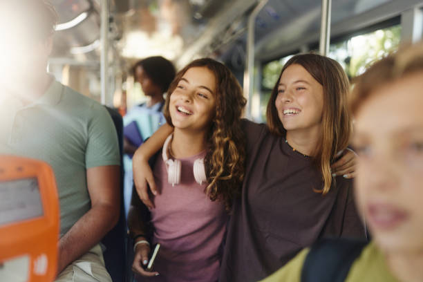 istock Happy schoolgirls embracing while traveling by a bus. 1927073126