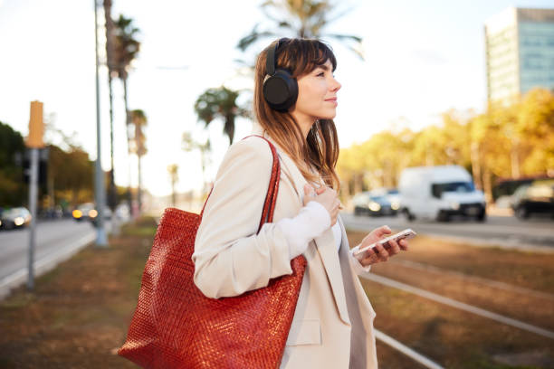 istock City Narratives: Businesswoman Absorbed in Podcast While Walking 1927074156