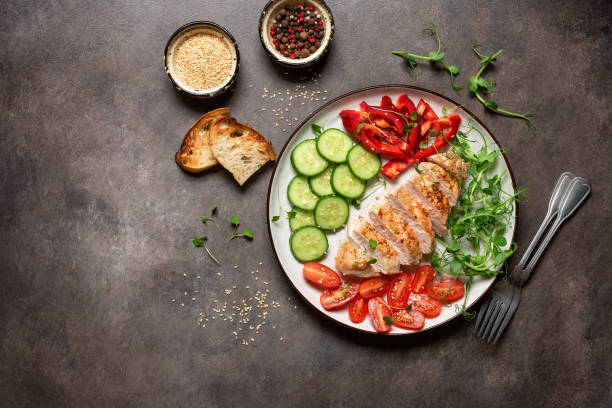 istock Grilled chicken fillet with fresh vegetables on a dark rustic background. Top view, flat lay 1927080036