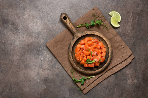 istock Raw salmon tartare with avocado served in culinary ring on dark rustic background. Top view, flat lay, copy space 1927080037