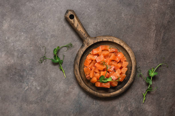 Raw salmon tartare with avocado served in culinary ring on dark rustic background. Top view, flat lay, copy space