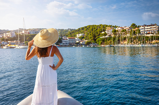 A tourist woman in a white summer dress looks at the village of Patitiri at Alonissos island, Sporades, Greece