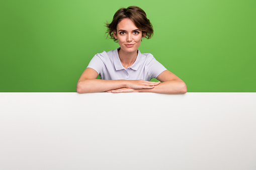 Photo of confident adorable girl wear trendy clothes presenting white placard blank empty space isolated on green color background.
