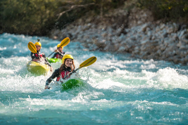 Thrill-Seekers Conquer Turbulent River Rapids Adrenaline-pumping action as mid-adult thrill-seekers of mixed genders paddle fiercely through the white-capped rapids of a fast-flowing river. rafting kayak kayaking river stock pictures, royalty-free photos & images