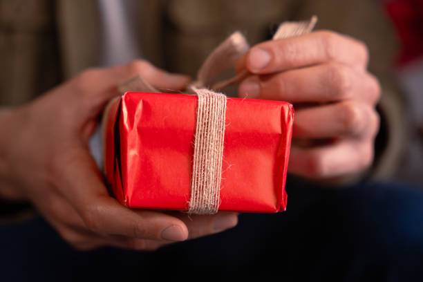 istock close-up Man's hands opening a Valentine's gift with a bow. 1927112811