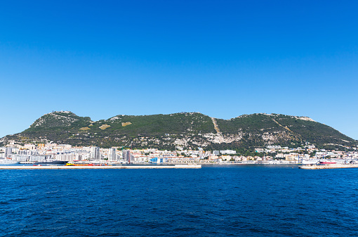 View from the sea to the port of Gibraltar. Bay, buildings, moored ships and yachts and the mountain.