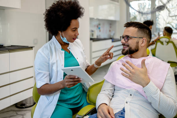 Modern dental consultation with tablet presentation In a modern dental consultation, a dentist utilizes a digital tablet to present diagnostic images and treatment details to an engaged patient tablet pc and digital hospital tools stock pictures, royalty-free photos & images