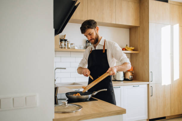 istock A man throws meat into a pan for cooking in the kitchen 1927175361