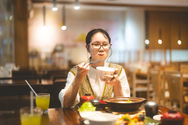 Happy asian woman holding rice bowl eating food at Japanese restaurant asia tasty from traditional culture Eating food at Japanese restaurant concept. Young adult asian woman holding rice bowl with tonkatsu miso menu. Enjoy meal happy face. Asia tasty from traditional culture. rice bowl restaurant stock pictures, royalty-free photos & images
