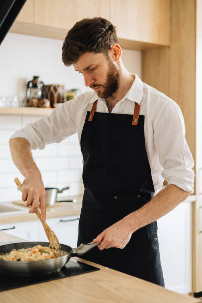istock A handsome man in an apron is cooking in a cozy kitchen at home 1927178687