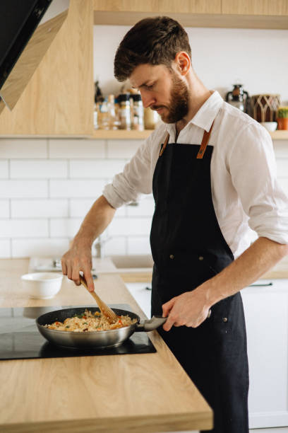 istock A handsome man in an apron is cooking in a cozy kitchen at home 1927178721