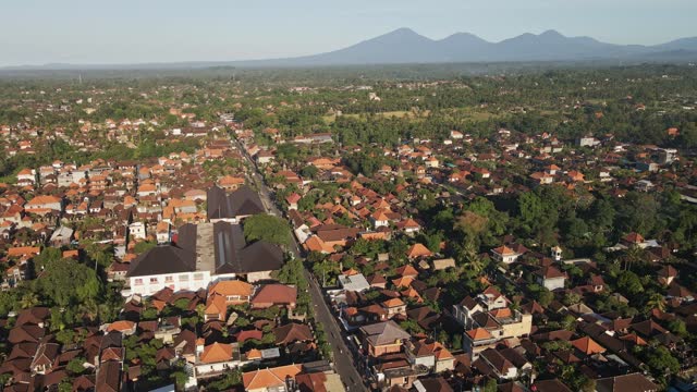 Establishing shot of Ubud downtown with traditional Balinese houses and volcanoes at the background, Bali, Indonesia