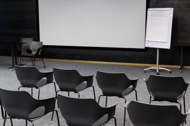 istock Empty conference room with rows of  grey chairs, media screen and whiteboard. 1927203448