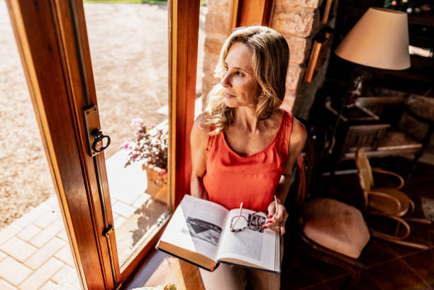 istock Mature woman contemplating while looking through the window at home 1927203984