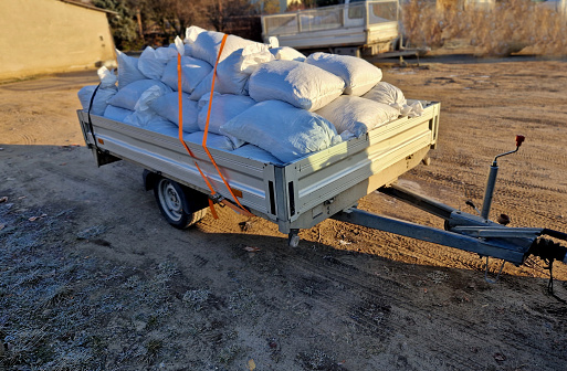 penalty fine, the small trailer behind the car is loaded with lots of bags of material. overloaded lifts will be stopped by police and fined for exceeding permissible weight of the vehicle and load. tied with strap