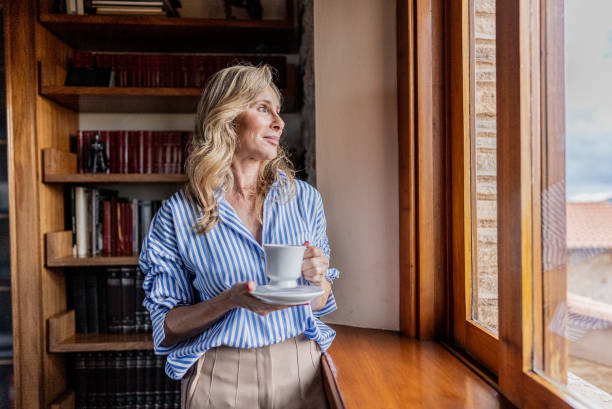 istock Mature woman contemplating while looking through the window at home 1927209450