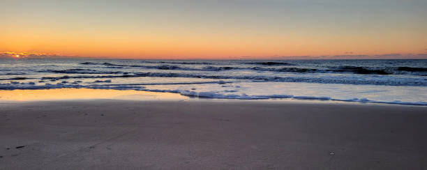 istock Sunset on the beach, with gentle waves rolling in and creating a delicate foam along the shoreline. 1927219631