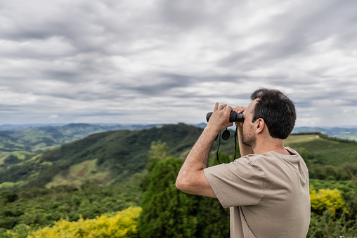 Mature man looking at view with a binoculars outdoors