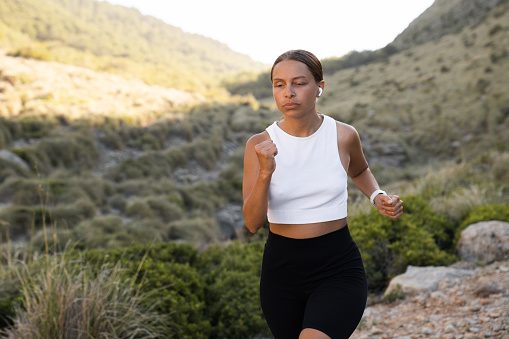 Caucasian female running jogging in the mountains outdoors, wearing sporty clothes, doing physical exercises, slimming, burning calories.
