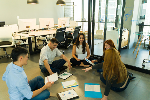 Group of workers laying some documents on the floor and sitting for a quick meeting in an office