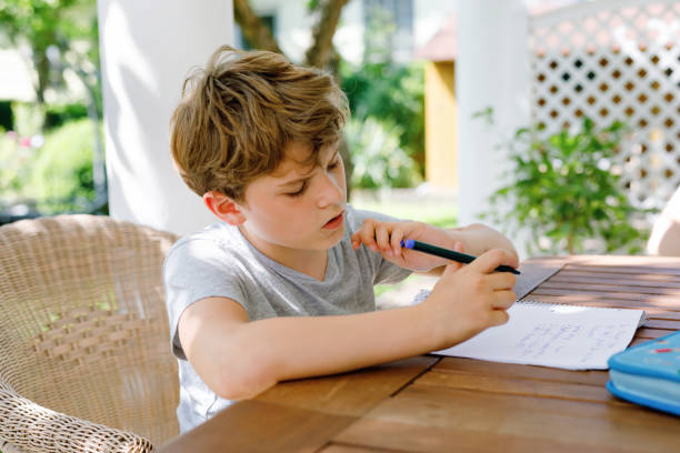 istock Hard-working sad school kid boy making homework during quarantine time from corona pandemic disease. Upset tired child on home schooling in coronavirus covid time, schools closed. 1927279996