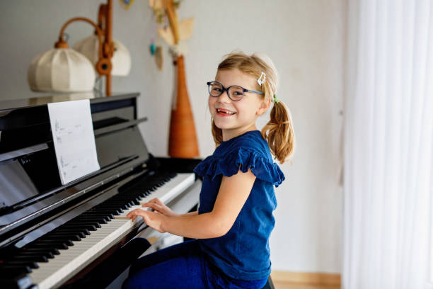 beautiful little preschool girl playing piano at music school. cute child having fun with learning to play music instrument. early musical education for children - piano keyboard instrument one person piano key ストックフォトと画像