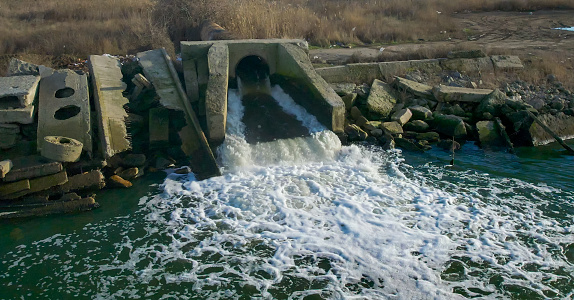 Environmental pollution with dirty sewage, water flows through a pipe into a pond, Ukraine
