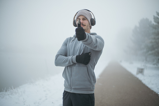 A young man stands outside in the winter in the fog