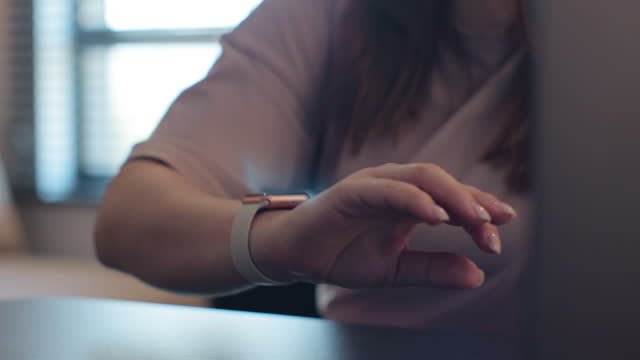 Woman fingers does double tap checking 3d rendering incoming notification on smart watch for hands-free interaction. Young woman is typing on laptop at the work table at the office.