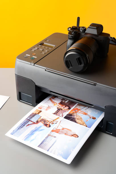 istock Printer and photo camera on table. Printing photos concept 1927347418