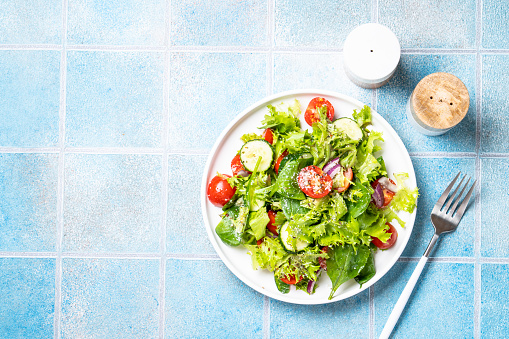 Green vegetable salad with fresh leaves on white plate. Healthy food, diet menu. Top view with space for text.