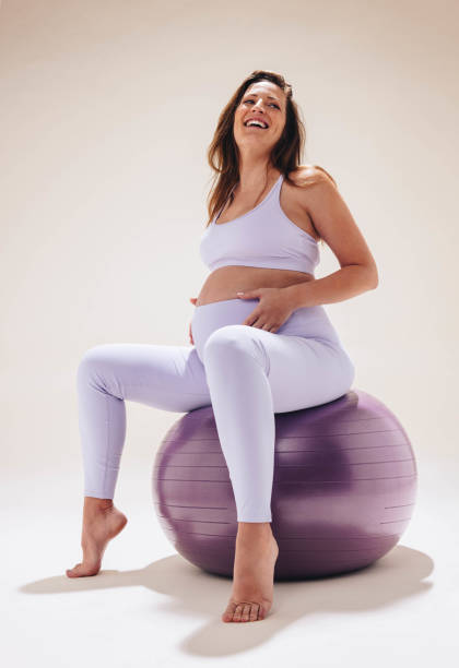 беременная женщина улыбается и тренируется на мяче для йоги для дородового фитнеса и хорошего самочувствия - human pregnancy prenatal care relaxation exercise ball стоковые фото и изображения