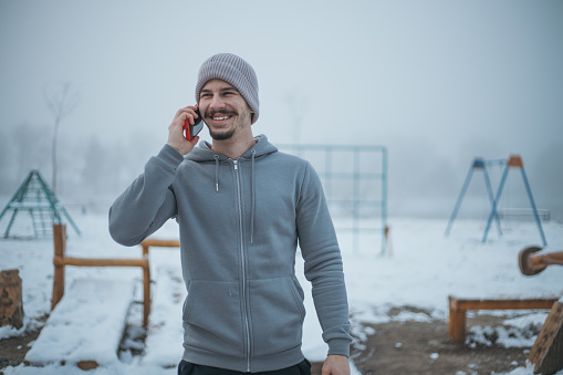 young man talking on the phone outside in winter