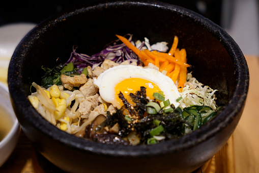 Close up Korean bibimbap served in a heated stone bowl